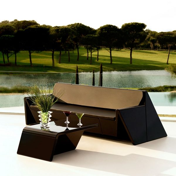 Image of brown Rest contemporary garden sofa and low table by A-cero for Vondom, shown on terrace with lake, lawn and trees in the background
