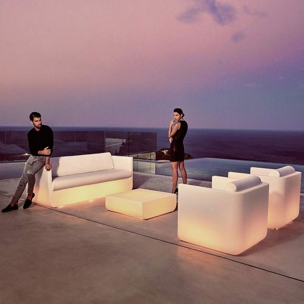 Image of illuminated Ulm garden sofa and lounge chairs at dusk on terrace with sea and sky in the background