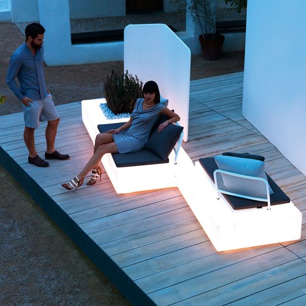 Image at dusk of Kes linear garden sofa by Vondom with white illumination within the furniture