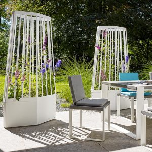 Image of pair of Air modern planters with trellis fitted with wheels, shown on terrace with plants and lawn in the background