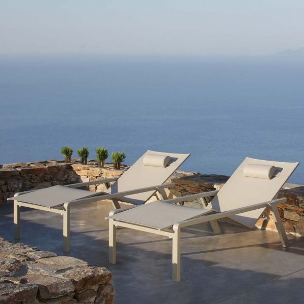Image of pair of white Alura sun loungers on terrace overlooking ocean in evening light