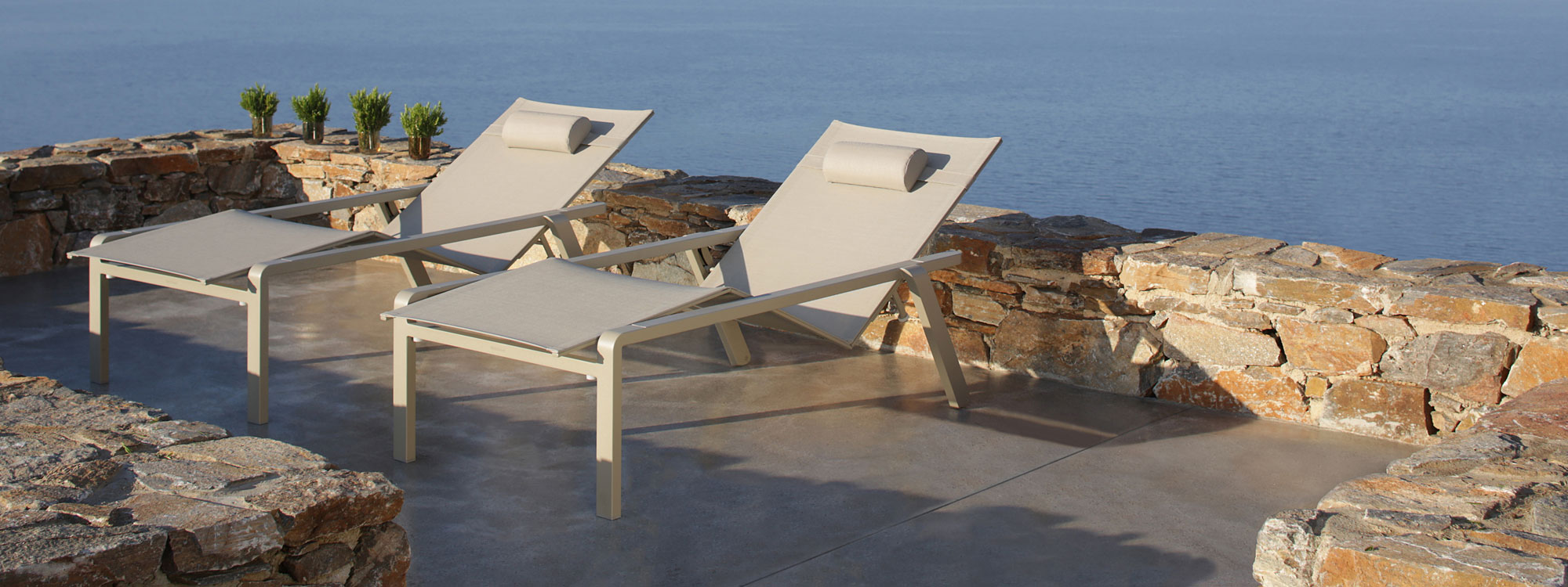 Image of pair of white Alura aluminium sunbeds by Royal Botania on terrace overlooking sea