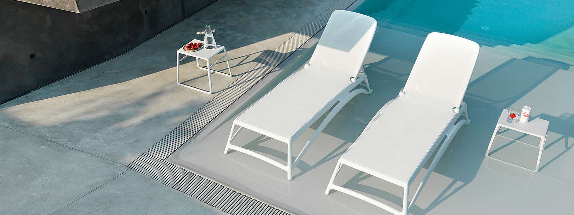Image of White POP Table & ATLANTICO Contract SUN LOUNGERS by Nardi, shown on minimalist poolside