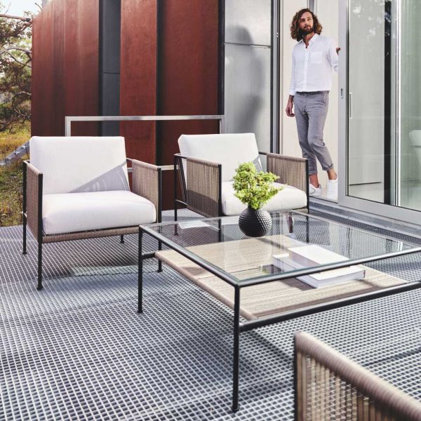 Swedish hipster stepping out onto terrace with Antibes modern garden furniture on outdoor carpet