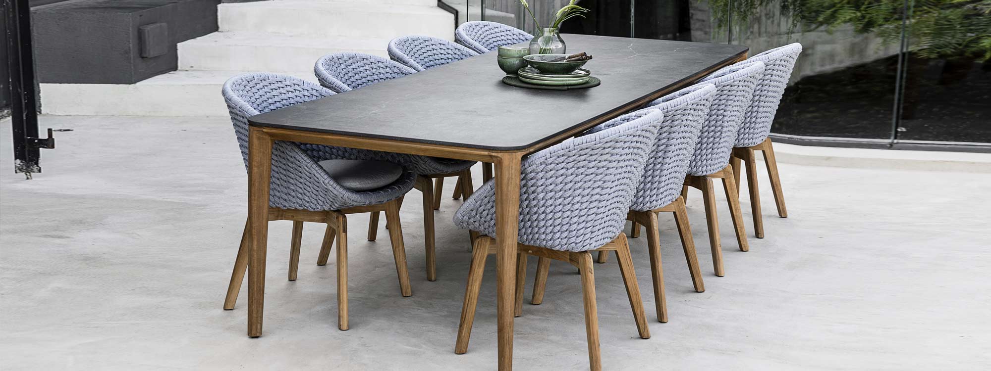 Image of Aspect rectangular teak table with black ceramic top and grey Peacock chairs by Cane-line outdoor furniture company