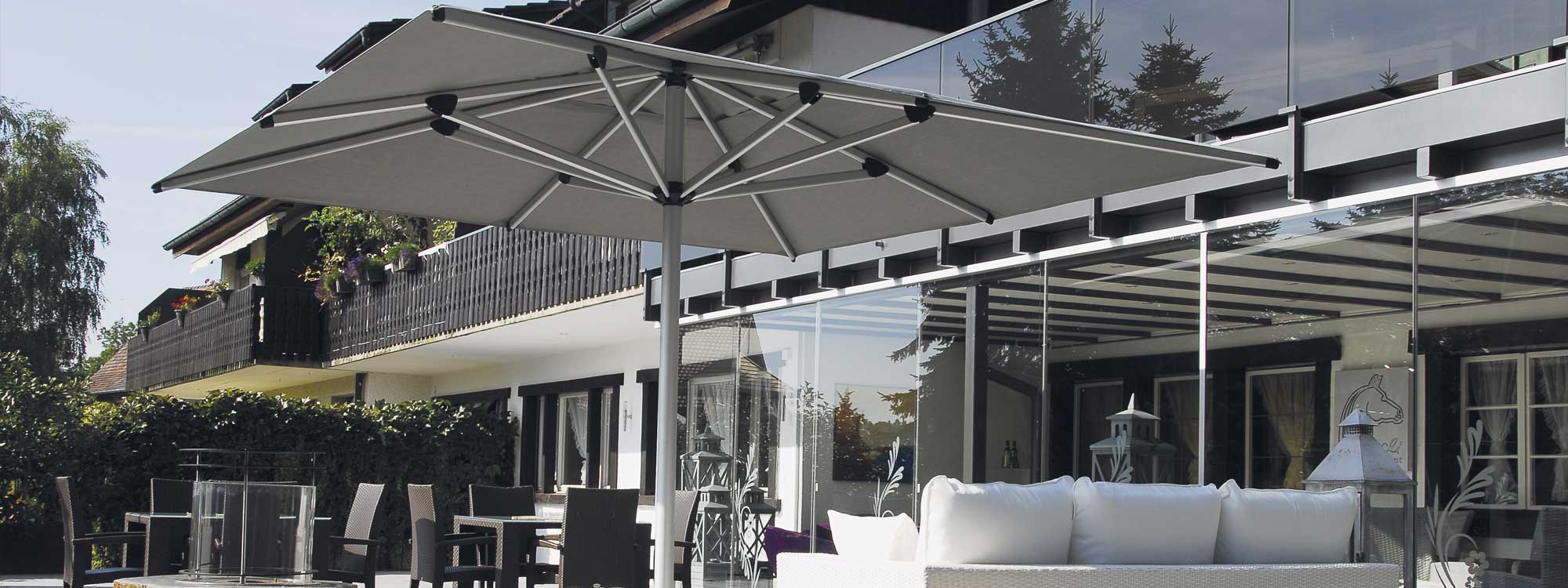 Image of Shademaker Astral large square mast parasol on terrace above lounge and dining furniture