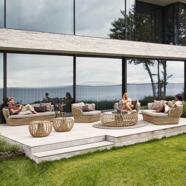 Image of large wooden decked terrace with Cane-line Basket and Nest furniture, shown in natural colored synthetic cane with taupe cushions