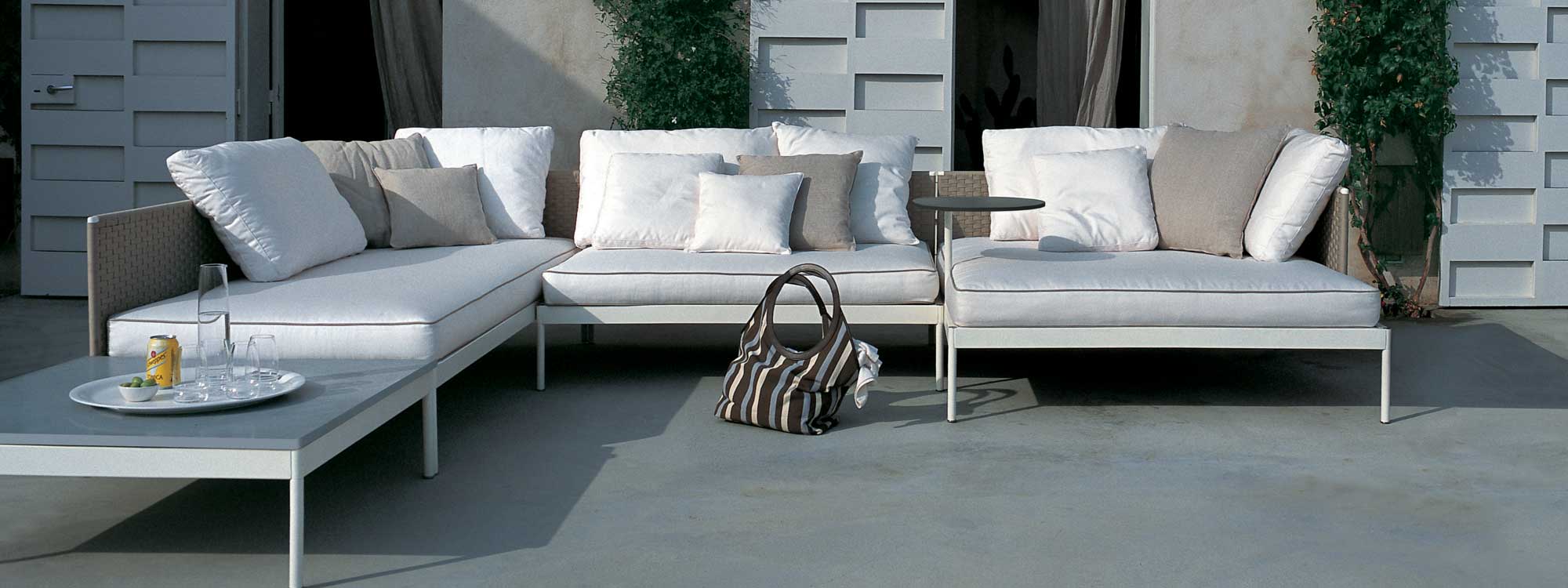 Image of RODA Basket white garden corner sofa with Sand-colored backs, shown in modern terrace