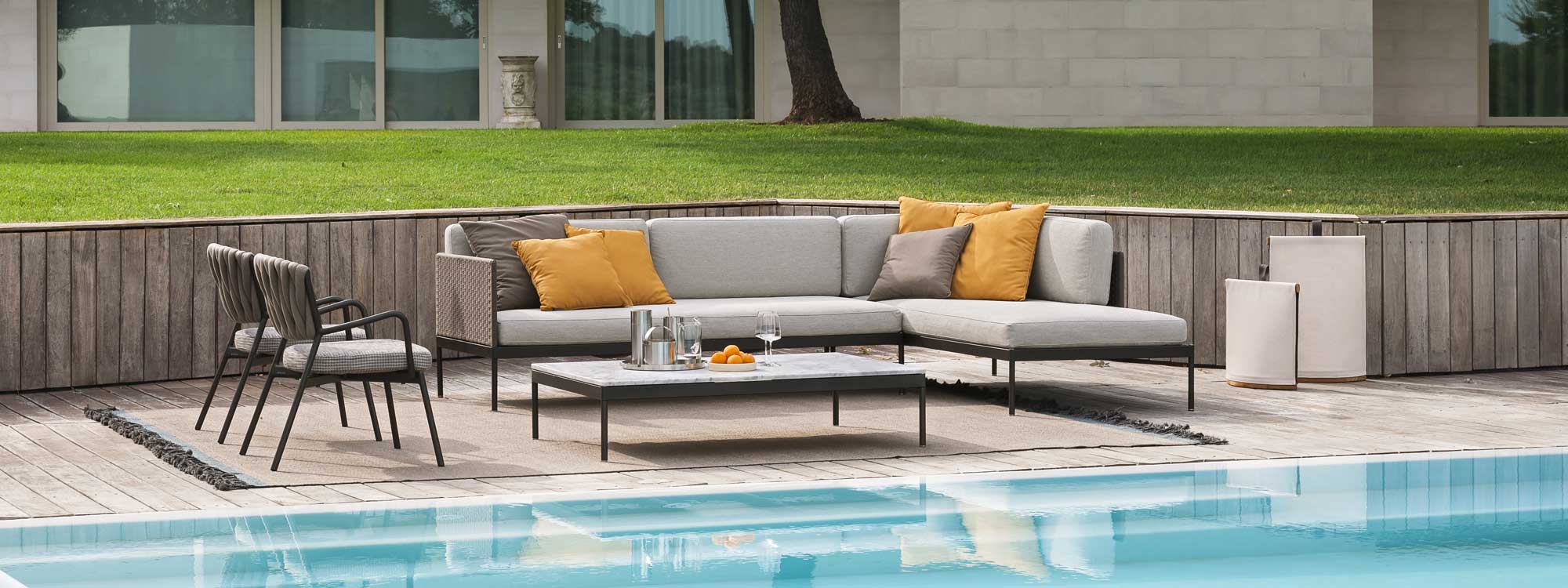 Image of Basket outdoor corner sofa and Piper chairs on sunken terrace with lawn and minimalist house in the background
