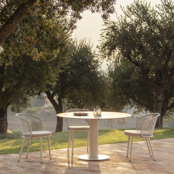 Image of 3 Baza white garden chairs and Branta small circular garden table in soft light of early evening