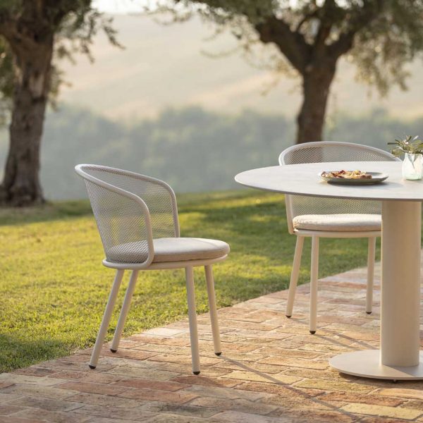 Image of Baza garden chair with tubular stainless steel frame and stainless steel mesh seat and back, next to Branta modern garden table
