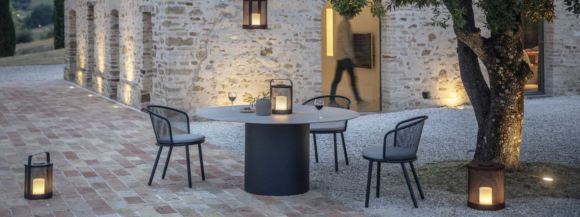 Dusk shot of Baza modern garden chair and Branta circular dining table designed by Studio Segers for Todus furniture company