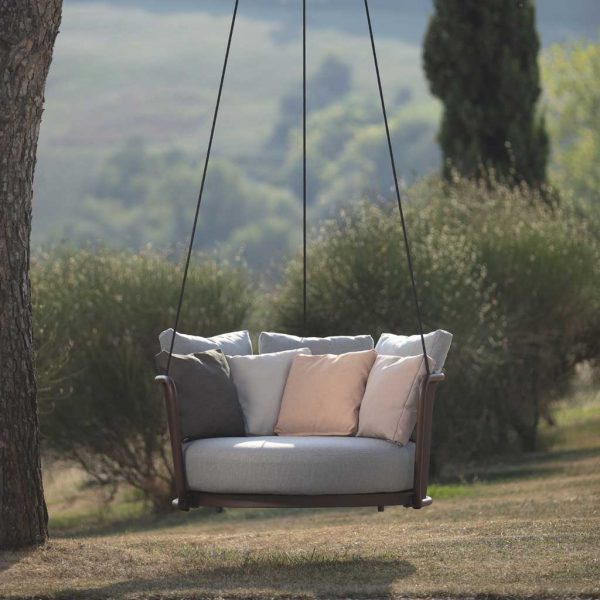 Image of Todus Baza modern swing seat with powder coated stainless steel frame and luxury Kvadrat outdoor cushion set, shown hung from branches of a tree