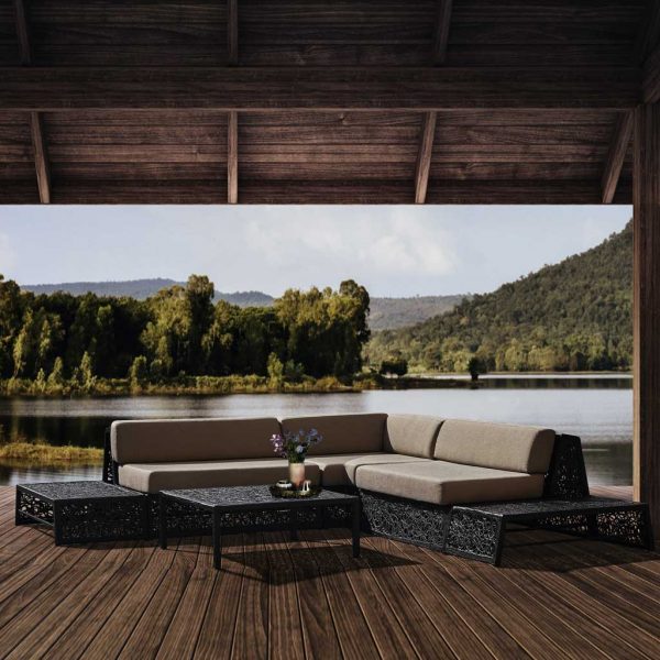 Image of black Bios Lounge outdoor sofa by Unknown Nordic, on decking beneath pergola, with lake and hills in background