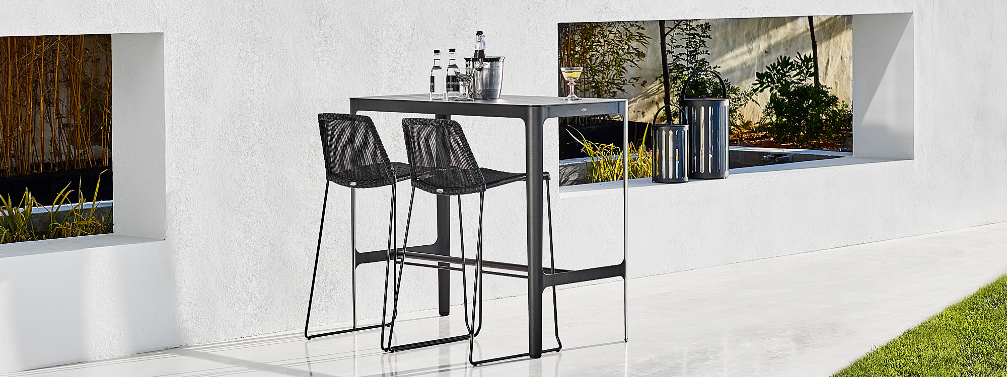 Image of black Cane-line Cut high table and black Cane-line weave bar chairs on white-washed terrace