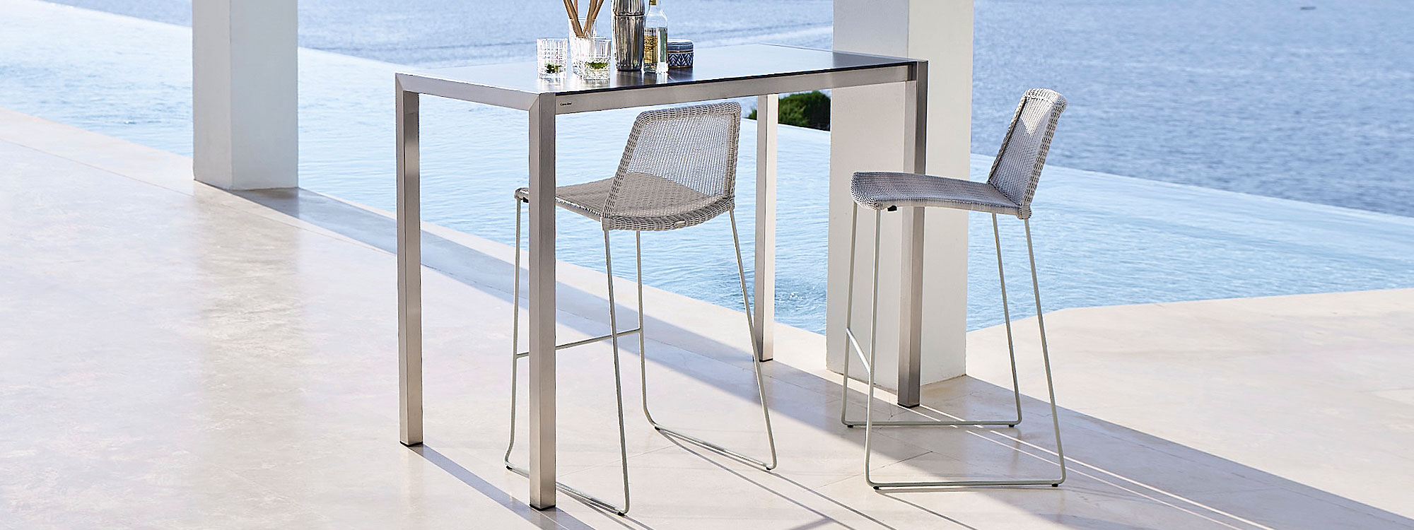Image of Cane-line Drop bar table and Breeze outdoor bar stools in light grey