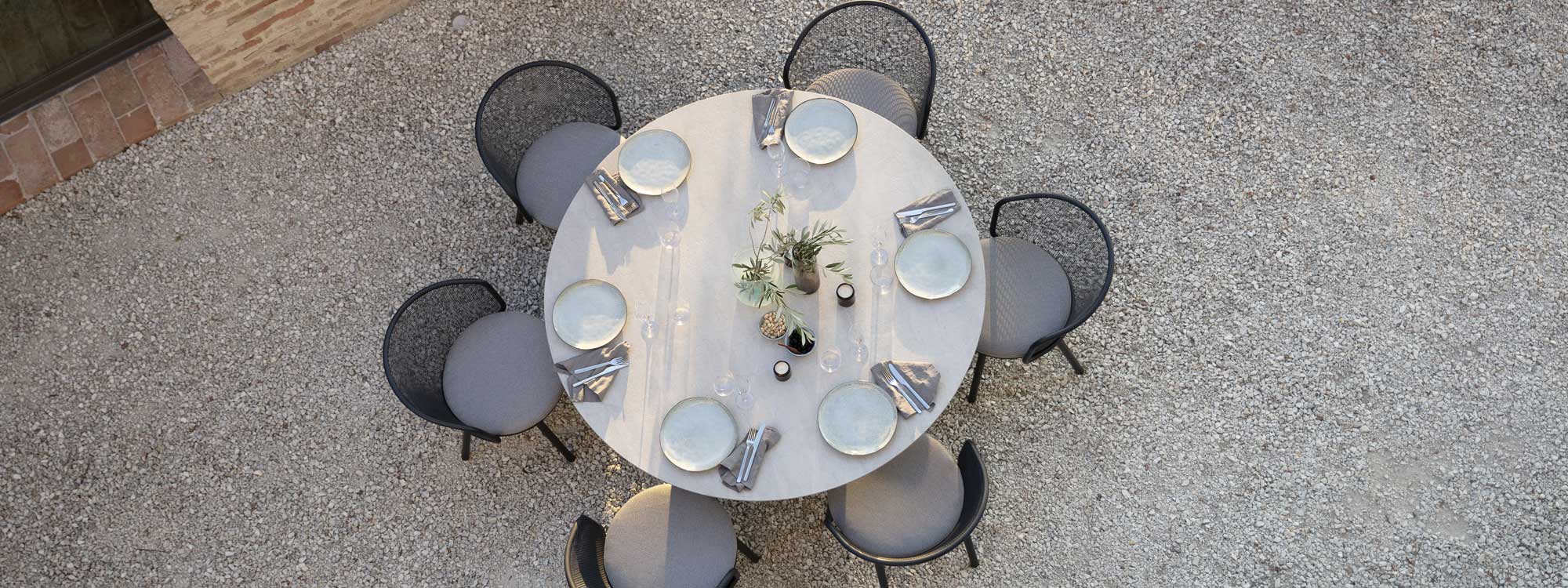 Birdseye view of Branta circular outdoor table and Baza garden chairs in gravel courtyard