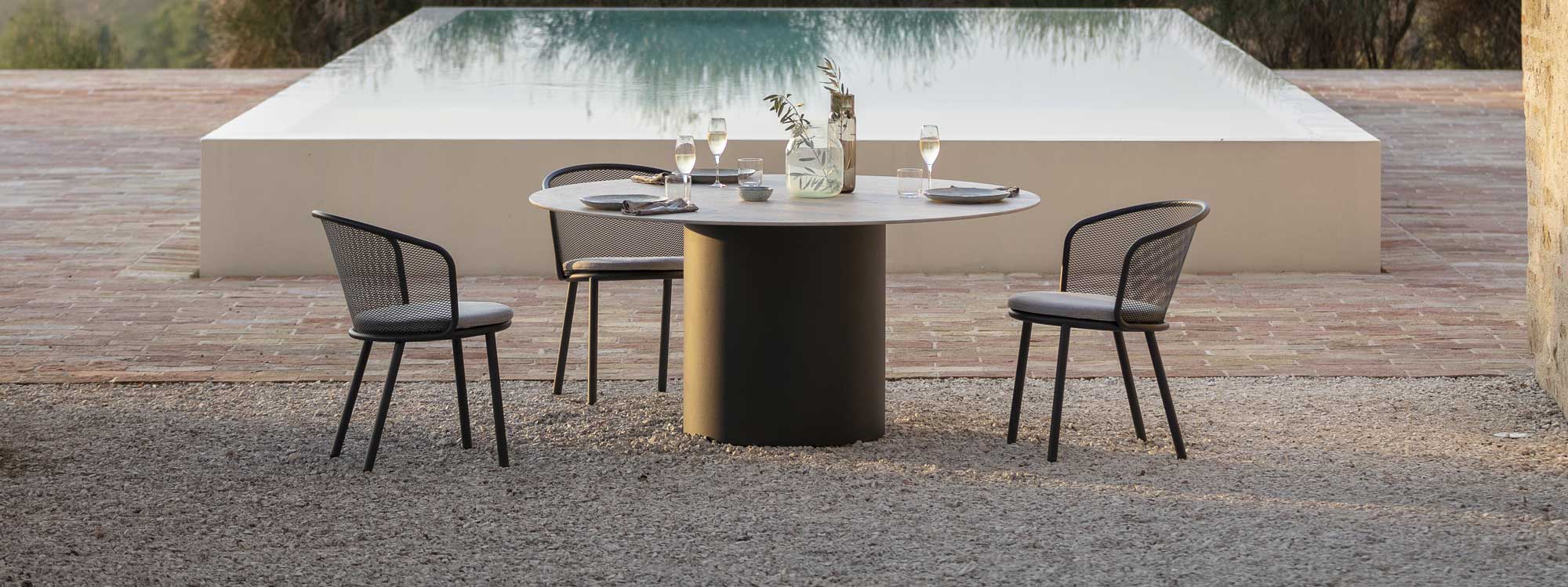 Branta round garden dining table and Baza garden dining chairs on terrace in early evening light