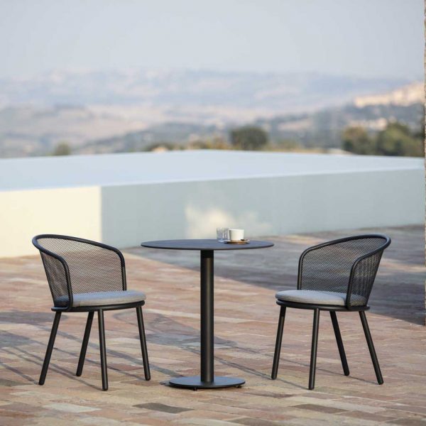 Image of Todus Branta small black garden table and Baza black garden chairs on sunny terrace with swimming pool and scorched countryside in the background