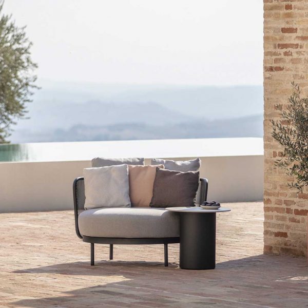 Branta round garden side table with Baza outdoor lounge chair on terrace with hazy hills in the background