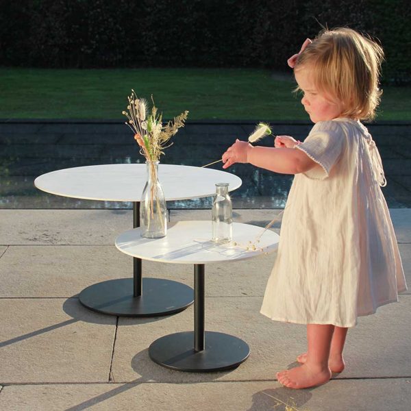 Sweet young girl looking at a flower next to Royal Botania Butler round low tables