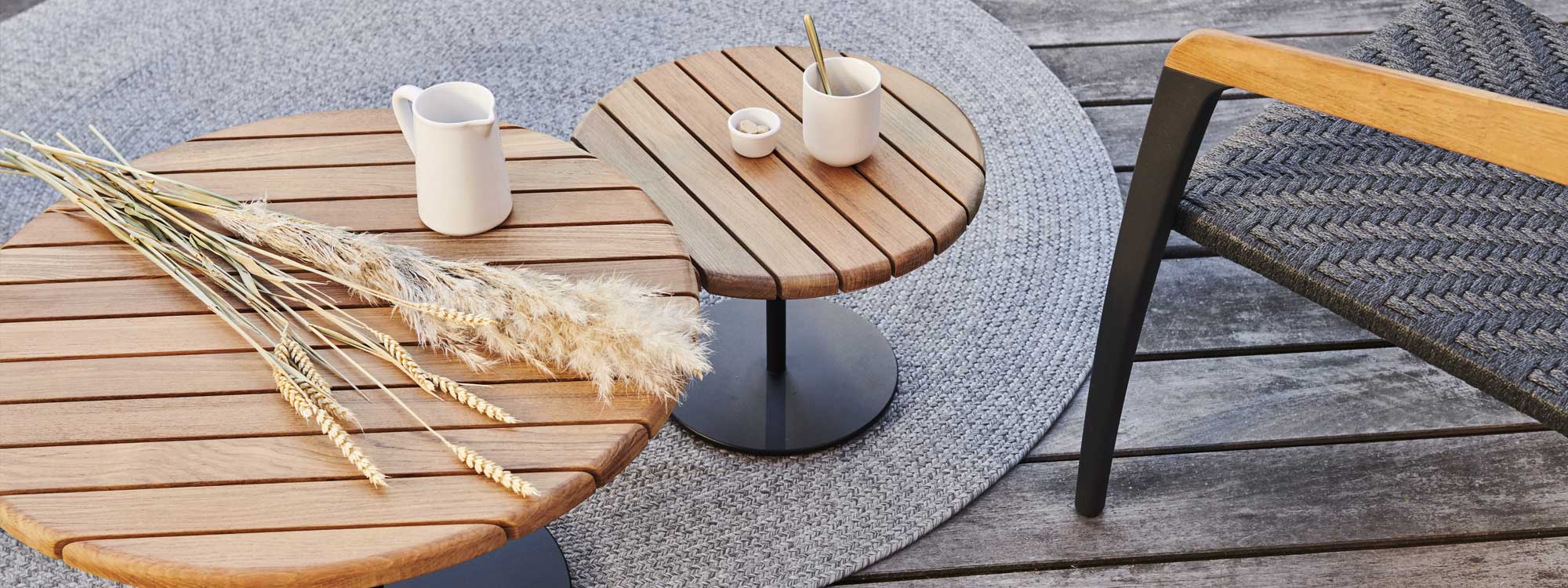 Image of Royal Botania Butler tables with planked teak tops and anthracite steel bases on circular outdoor rug