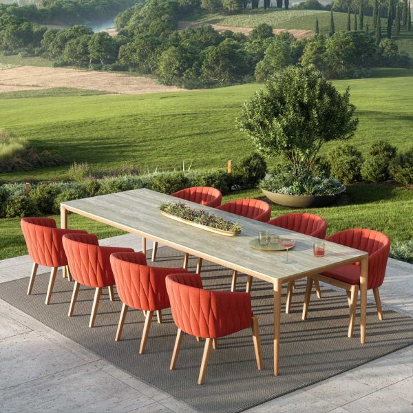 Royal Botania Calypso chair and U-nite garden table on sleek terrace with undulating countryside in background punctuated by Cypress trees.