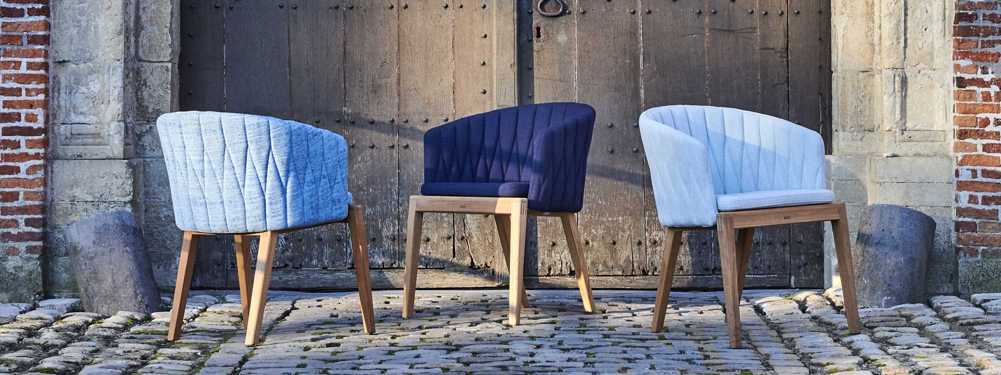 Image of Royal Botania Calypso chairs with blue upholstery, shown in cobbled courtyard