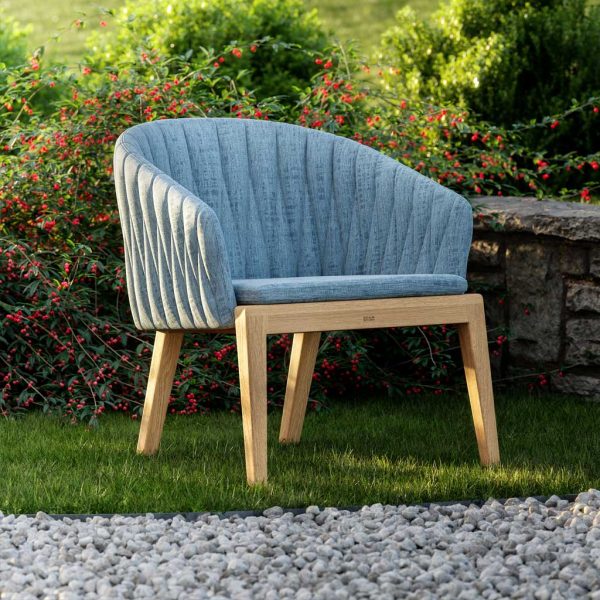 Image of Royal Botania Calypso lounge chair with teak frame and blue upholstery, sat on green grass