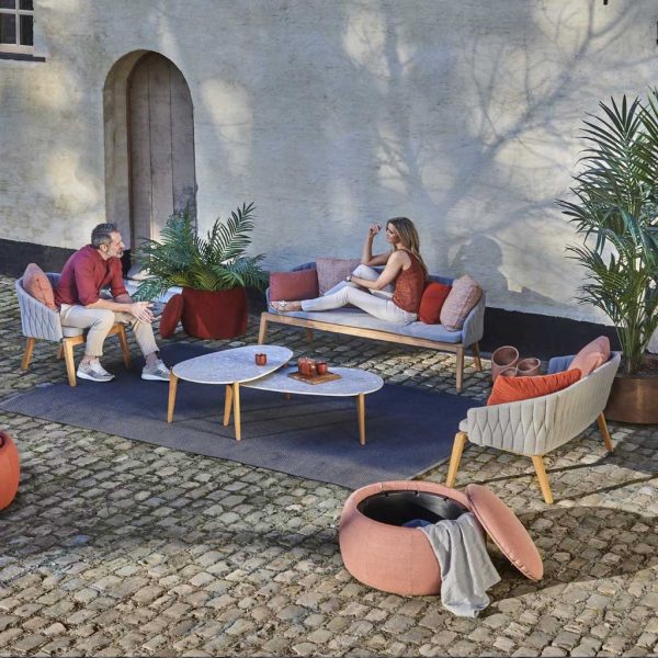 Image of couple relaxing in cobbled courtyard on Royal Botania Calypso garden sofas