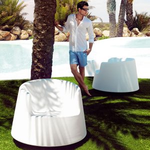 Image of man stood in between pair of Roulette wide garden rocking chairs by Vondom beneath shade of palm tree
