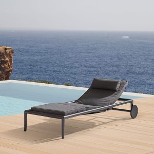 Image of grey Cane-line Conic sunbed with cushion on poolside with sea in background
