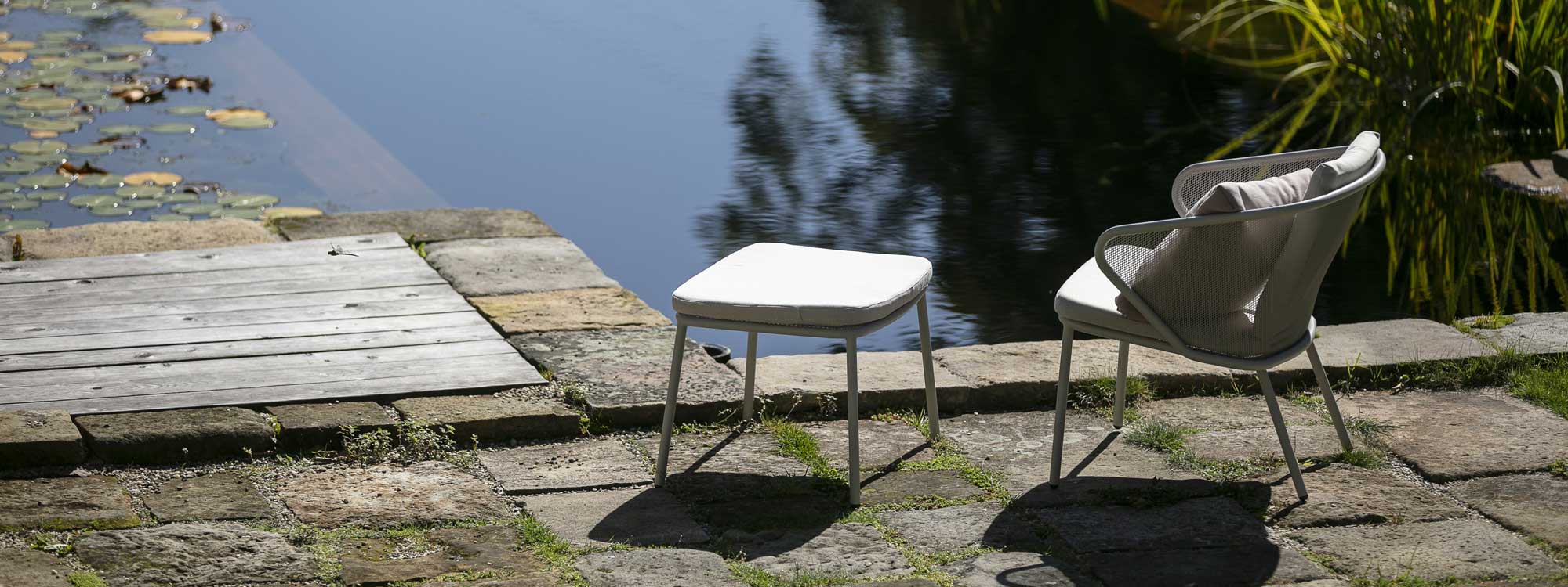 Image of white Condor contemporary garden chair and footstool on stone floor by water feature