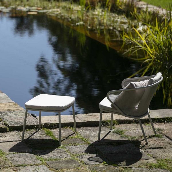 Image of Todus Condor garden easy chair and foot stool on terrace in front of tranquil water feature