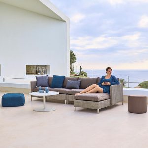 Image of lady relaxing on Caneline Connect modular garden sofa, which is shown in Taupe Cane-line Weave