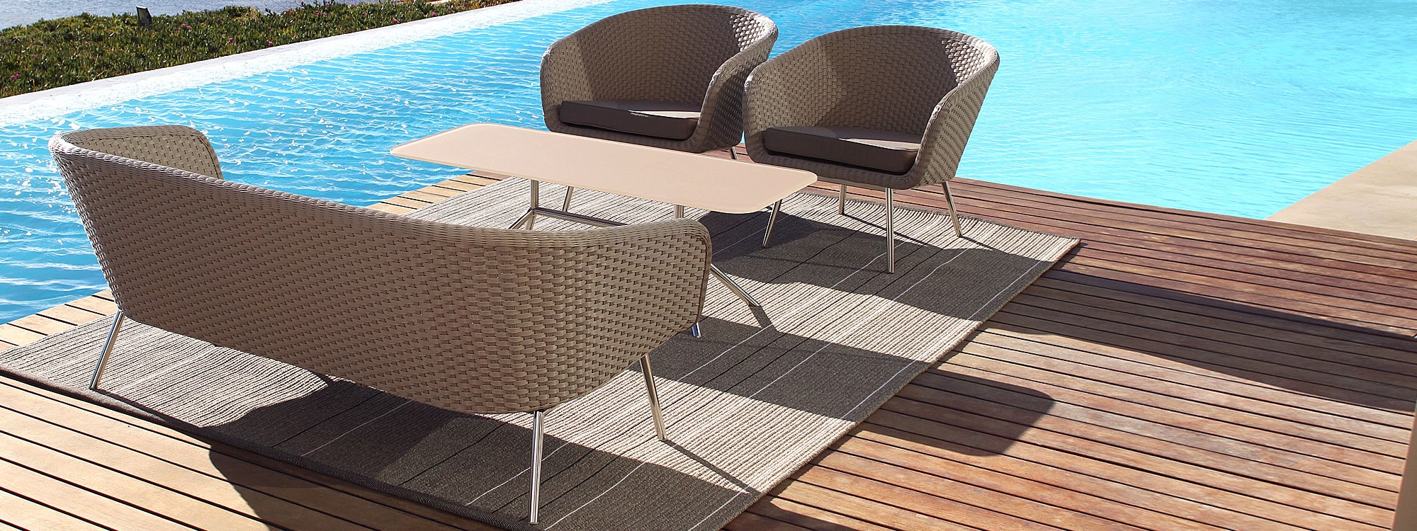 Image of Shell retro-inspired outdoor sofa and lounge chairs in taupe Batyline fibre and electro-polished stainless by FueraDentro, on wooden decking next to swimming pool