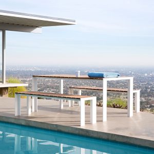 Image of Stua Deneb large garden table and benches with white aluminium frames and slatted teak surfaces, with smoggy cityscape in the background
