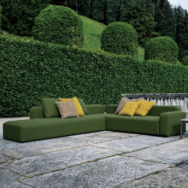 Green Dandy garden sofa in front of large hedge