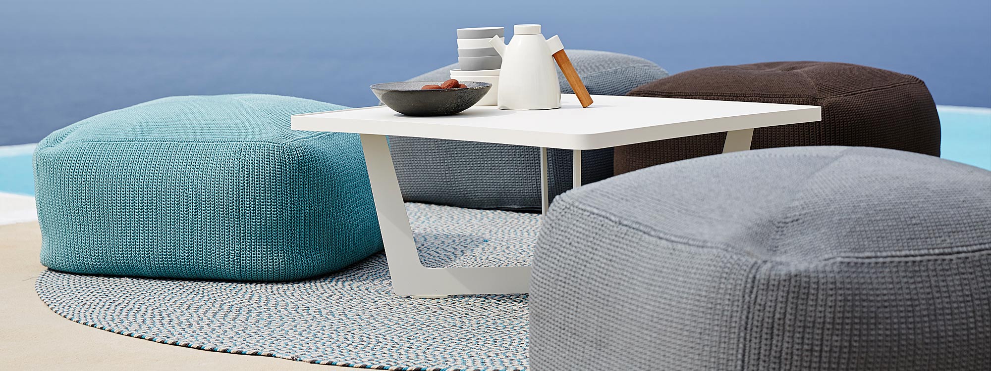 Image of Caneline Divine garden poufs in 3 different colors, together with Time Out white garden coffee table