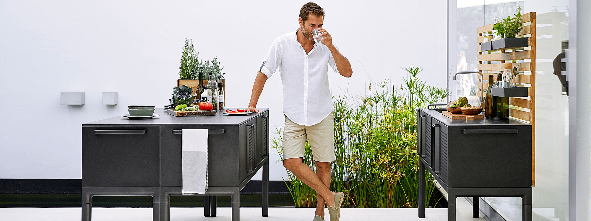 Image of man leaning on Drop outdoor kitchen island by with ceramic top by Cane-line