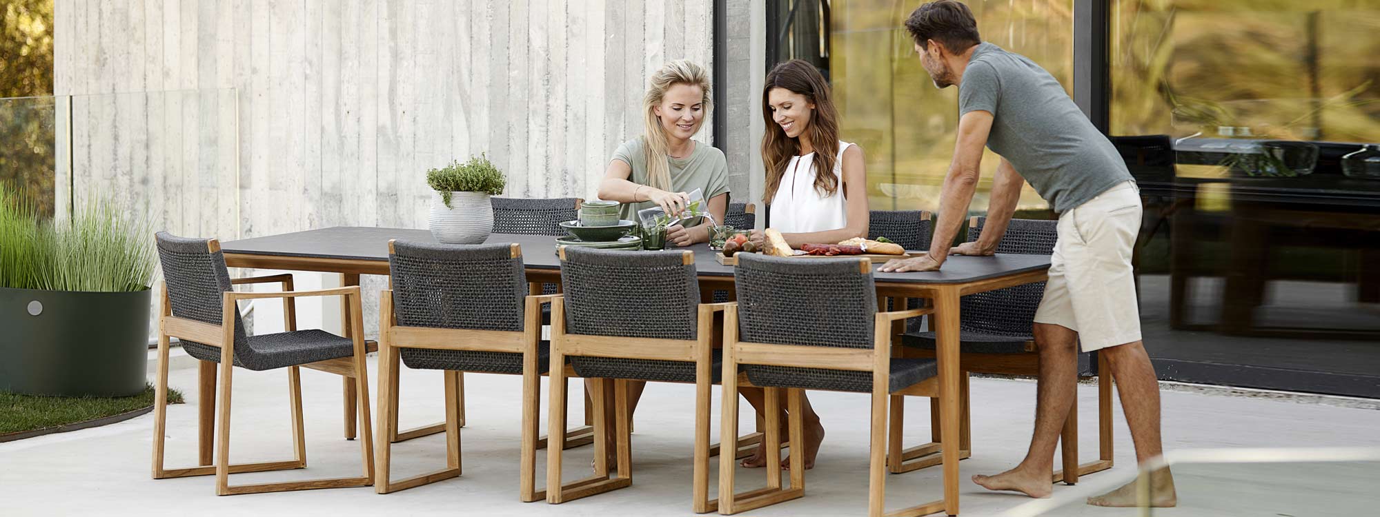 Image of large Aspect rectangular teak table with black Fossil ceramic top, together with Caneline Aspect garden chairs in teak and dark-grey SoftRope