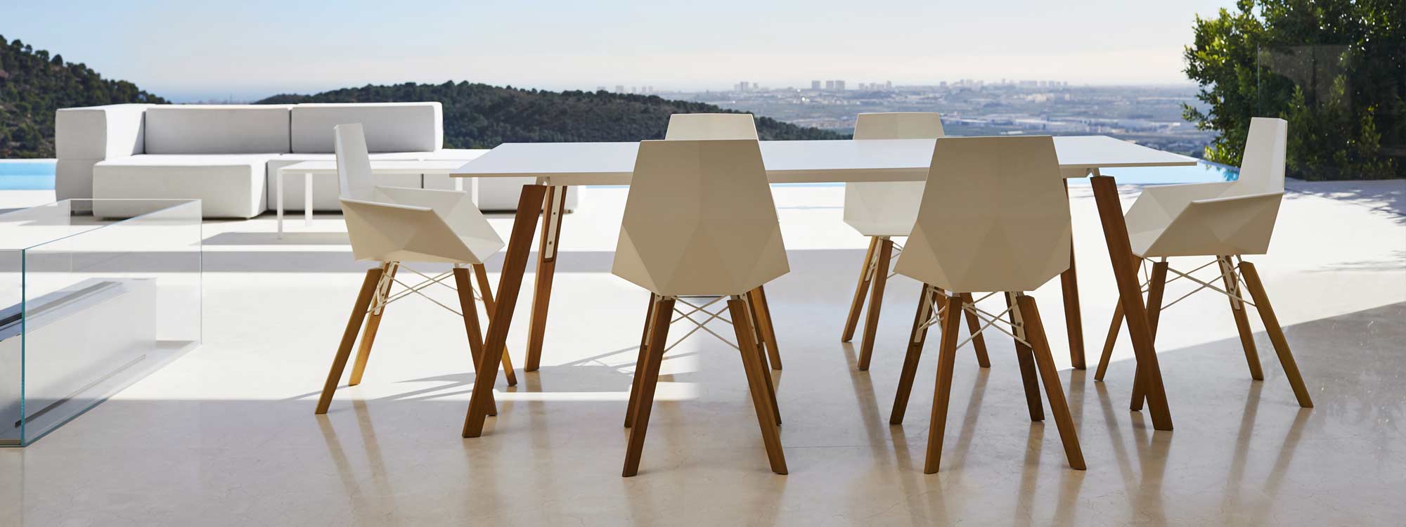 Image of Vondom Faz Wood modern dining set on minimalist terrace with cityscape in the background