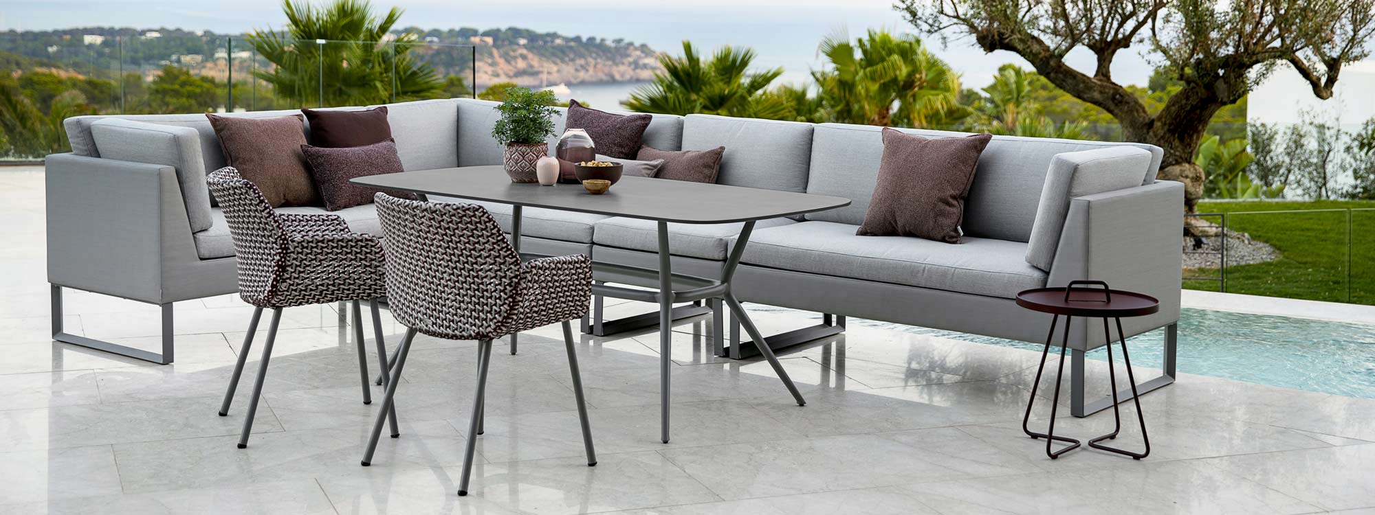 Image of Flex corner dining sofa and Joy table by Cane-line on Mediterranean terrace with sea in background