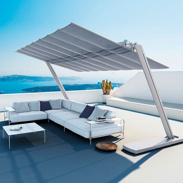 Image of Coro Sabal corner sofa beneath Flexy Zen retractable awning, on sunny terrace with sparkling blue sea in the background