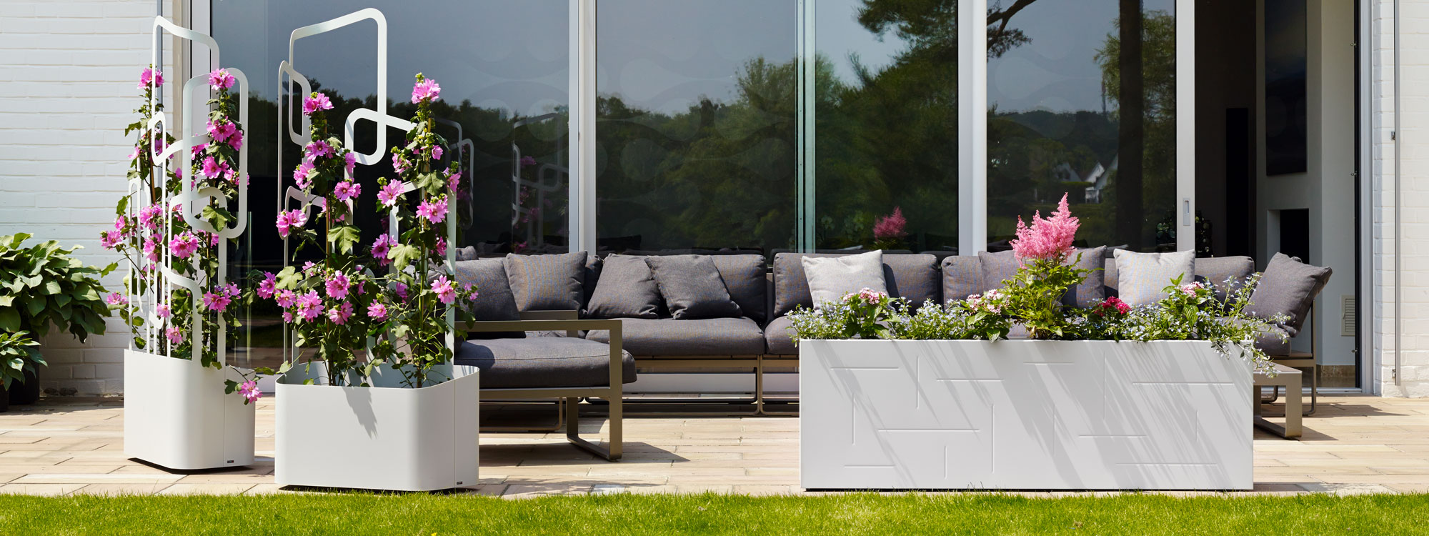 Image of pair of Flora Paro planters with wheels shown in sunny terrace next to a modern garden sofa