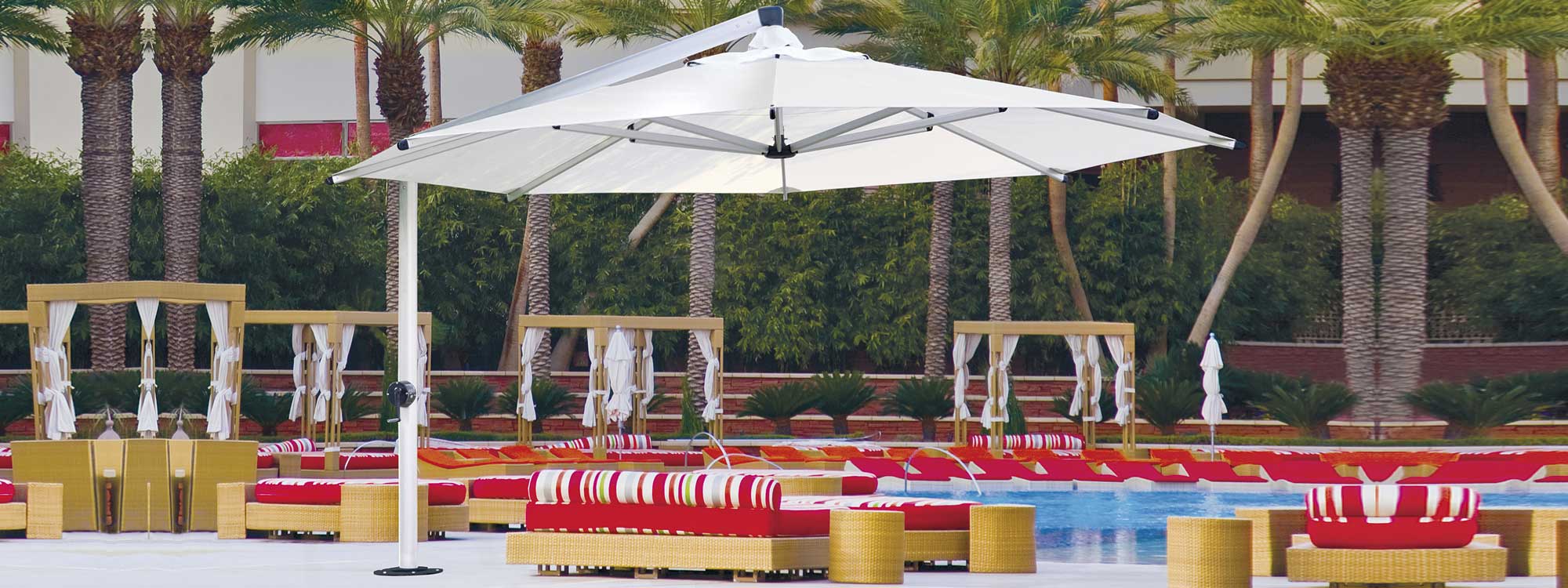 Image of Shademaker Galaxy large white cantilever parasol over outdoor lounge furniture on a hotel poolside