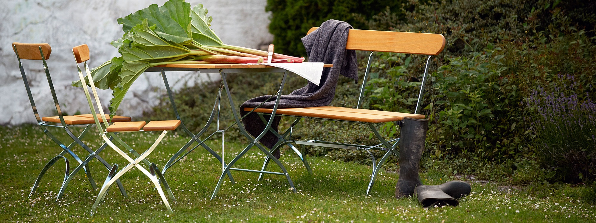 Image of Brewery traditional folding garden furniture by Grythyttan Stålmobler Swedish furniture, shown with bunch of rhubarb stems on the table.