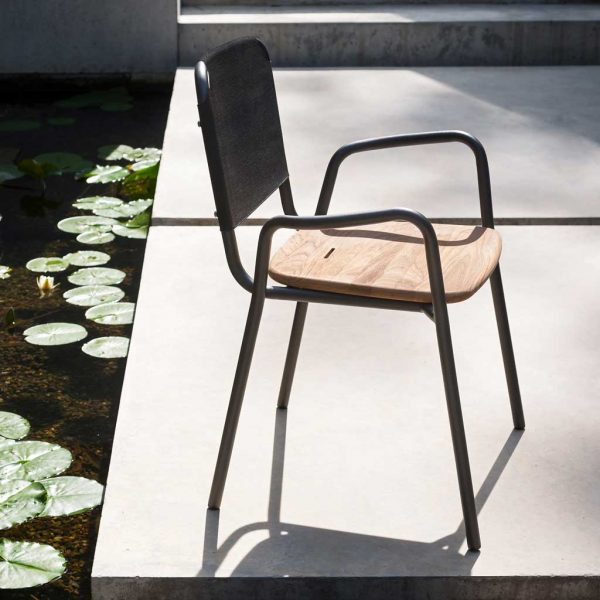 Peaceful image of RODA Guest garden armchair on terrace next to tranquil water feature with lily pads