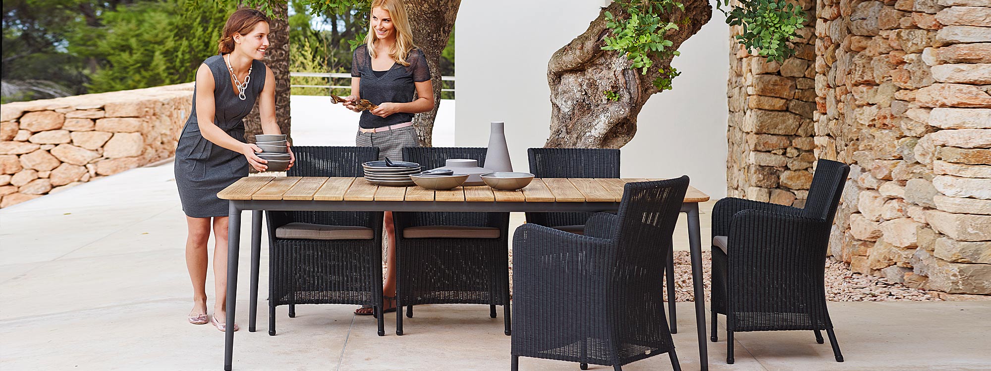 Image of Caneline Hampsted black cane garden chairs around Core garden table with Lava Grey base and teak top