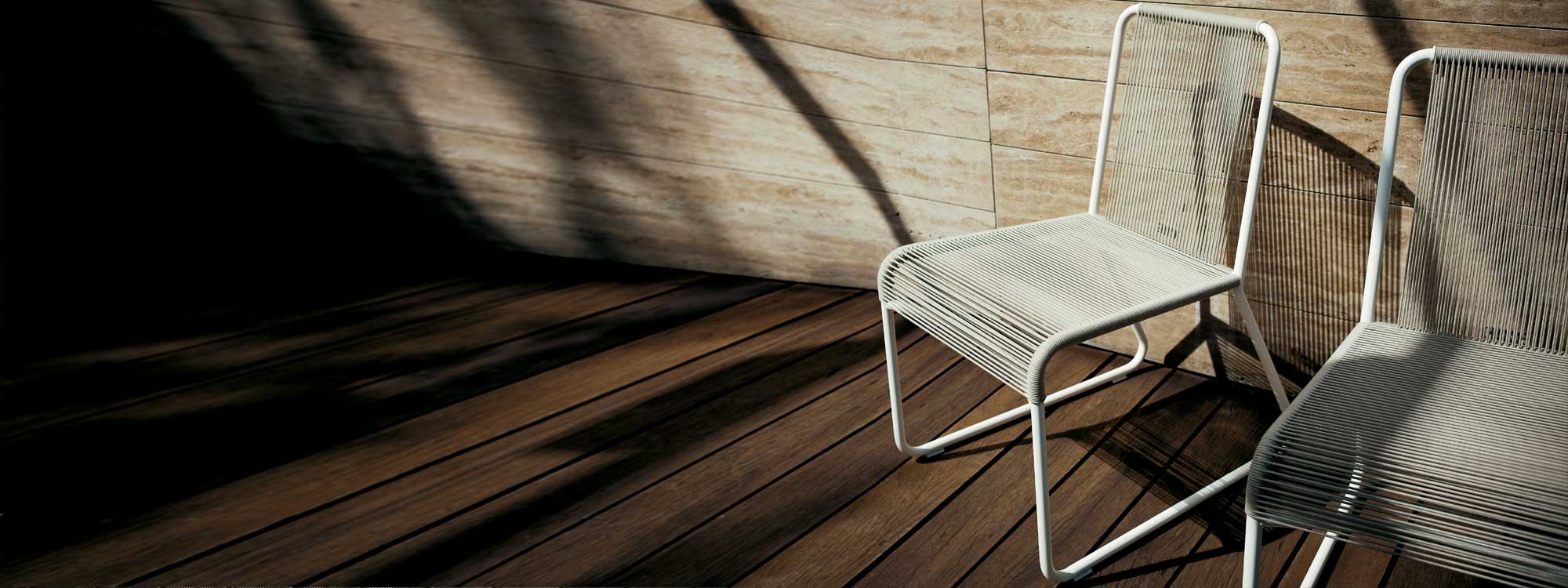 Image of pair of RODA Harp white garden chairs with sand acrylic cord seat and back shown on wooden decking in light and shade